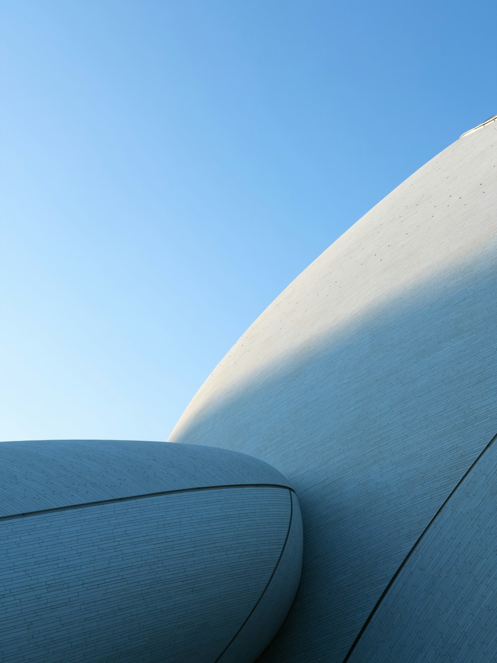 Curved white architectural form against a blue sky